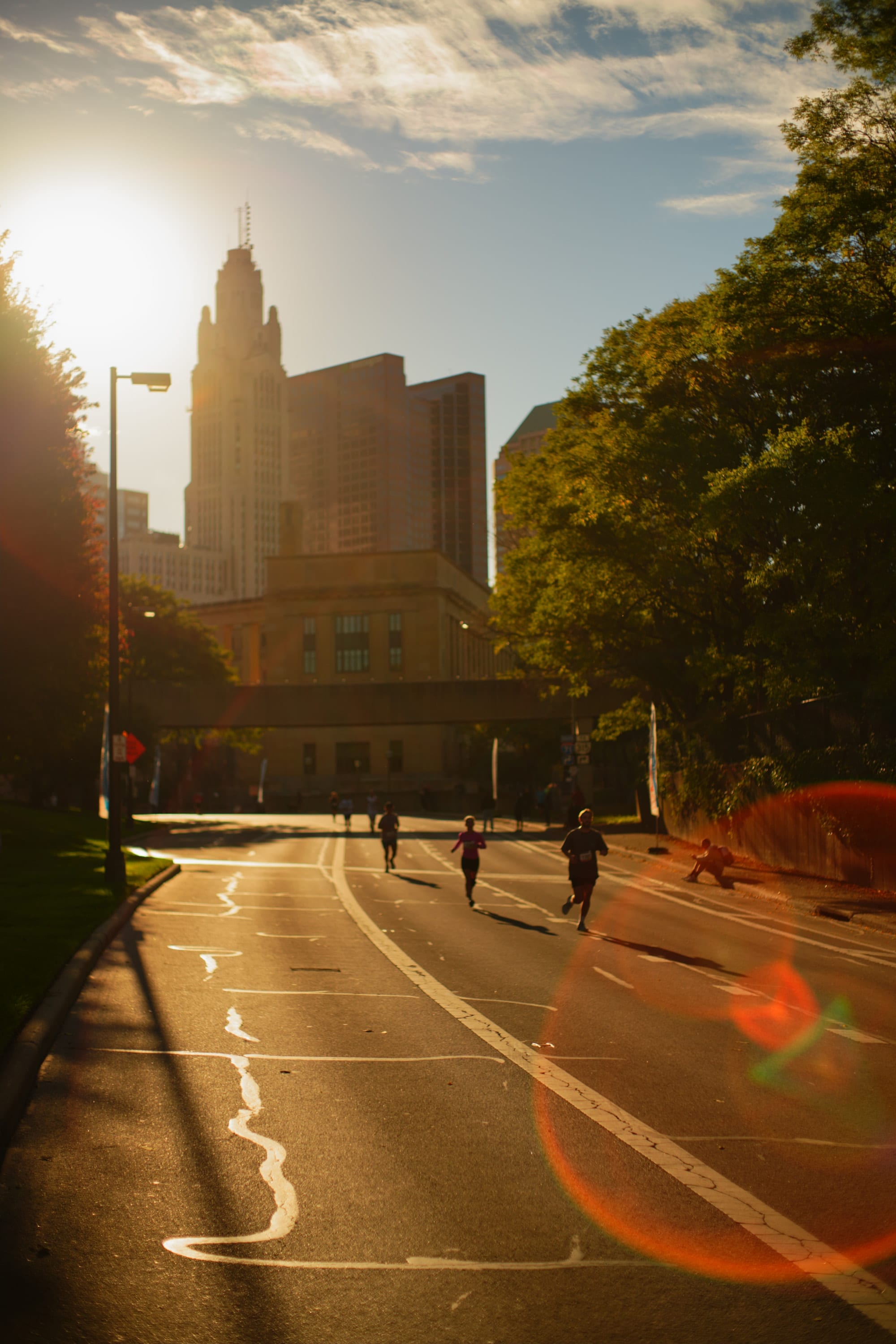 The downtown skyline backlit by the low sun, a few runners on the empty road below.